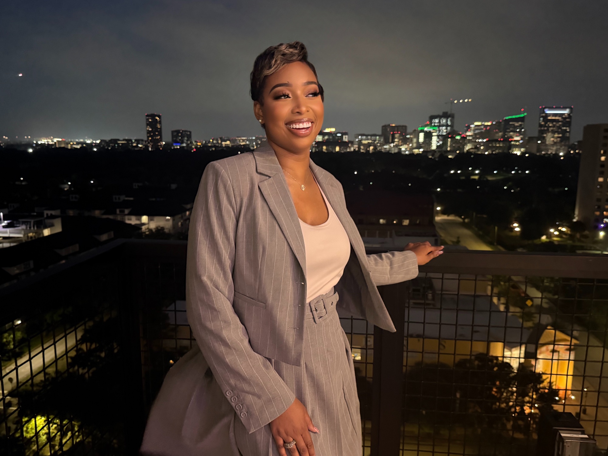 Diamonn Rose wearing a gray suit against a nighttime city skyline